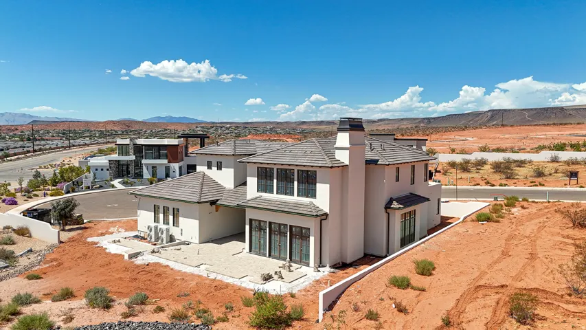 Stucco exterior with multiple rooflines, a prominent chimney, and a paved patio area