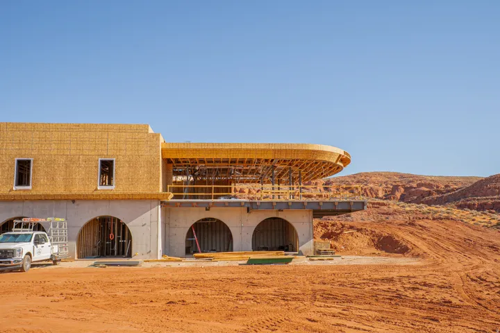Construction framing with sheathing, arched concrete openings, and a rounded second-story structure