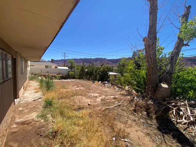 Expansive outdoor space with mature trees, a clear blue sky, and distant mountain backdrops