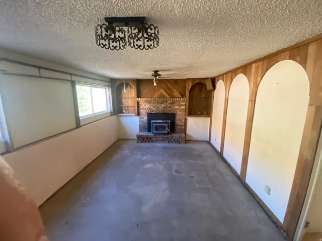 Brick-clad fireplace with wood-burning stove, built-in shelving, and wood-paneled walls with arched alcoves