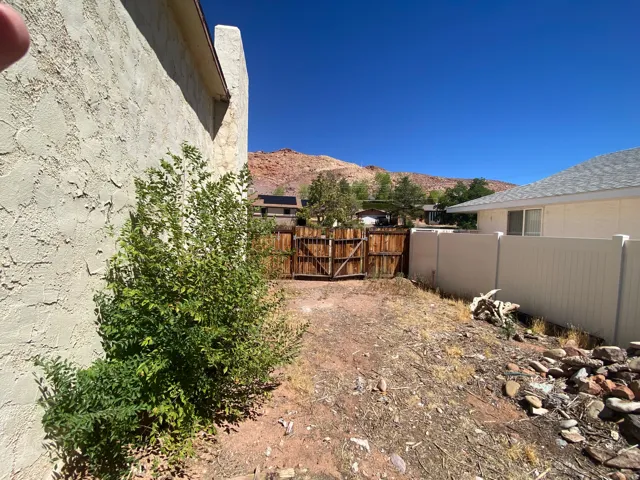 Stucco exterior with a peaked roofline, wood fencing, and a privacy fence