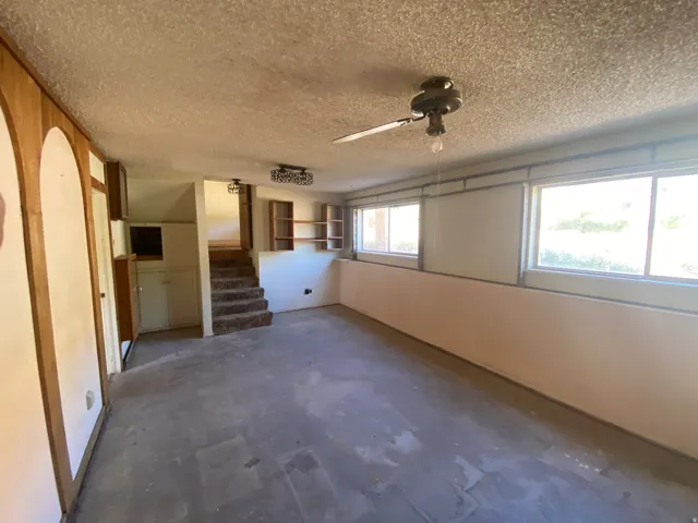 Two windows providing natural light, built-in shelving, and a ceiling fan