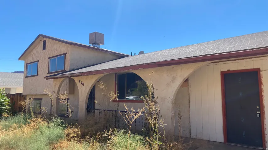 Stucco exterior with arched entryway, asphalt shingle roof, and visible house numbers