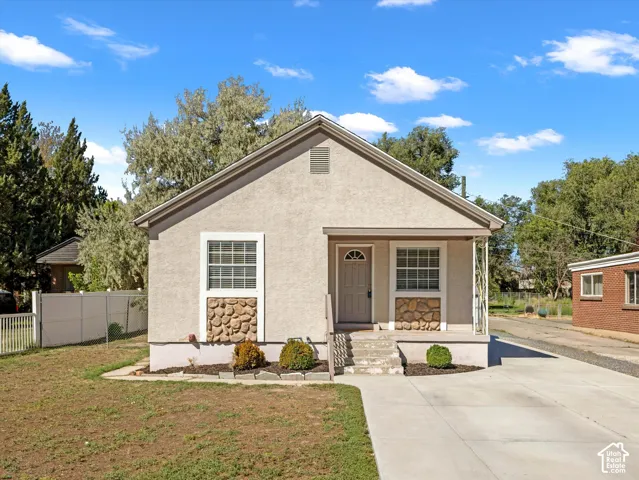 Stucco exterior with stone accent detailing, covered entryway, and concrete driveway