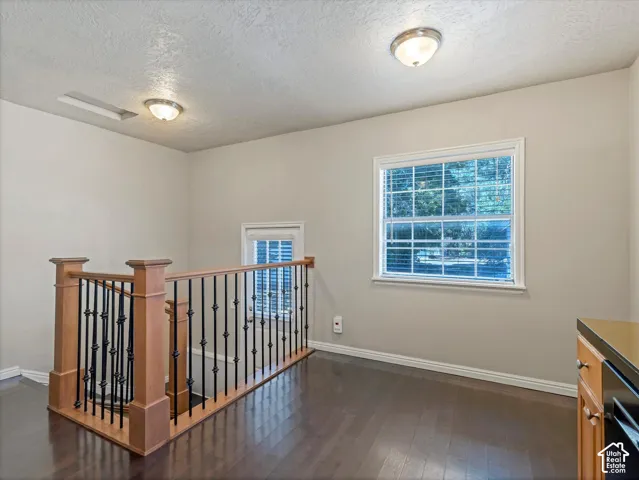 Wood-finish flooring, staircase with wood newel posts and wrought iron balusters, recessed lighting, and a large window