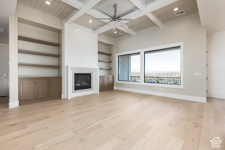 Expansive living space featuring wood-finish flooring, coffered ceilings, and a built-in fireplace with a stone surround