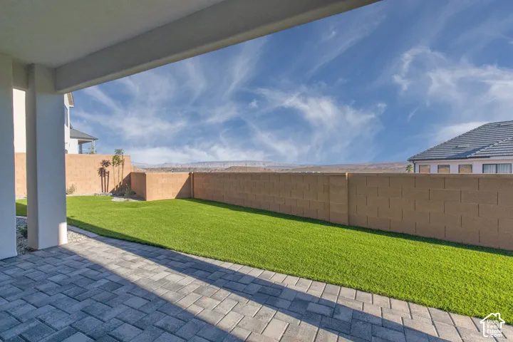 Expansive backyard featuring a manicured lawn with mature landscaping, bordered by composite fencing