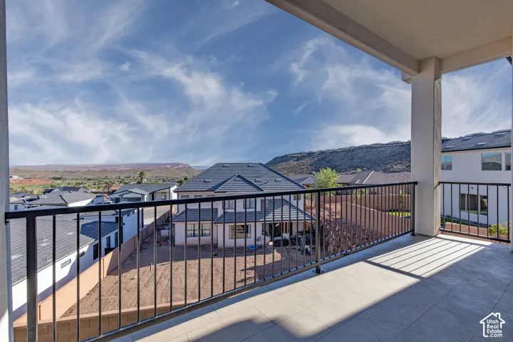 Upper-level balcony featuring a patterned concrete surface, black metal railings, and structural columns