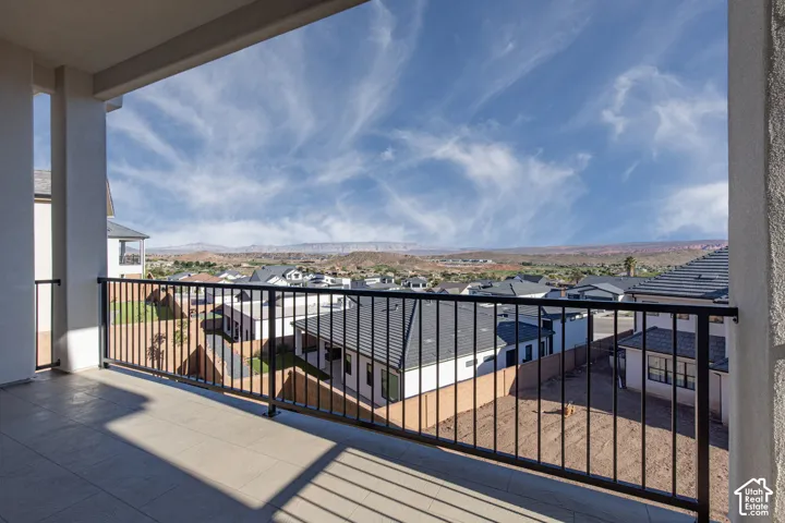 Expansive balcony featuring a black metal railing, tiled flooring, and stucco columns