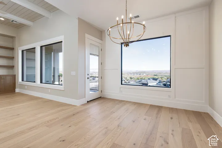 Light wood-finish flooring, large picture windows, wood-paneled accent wall, coffered ceiling, and built-in shelving