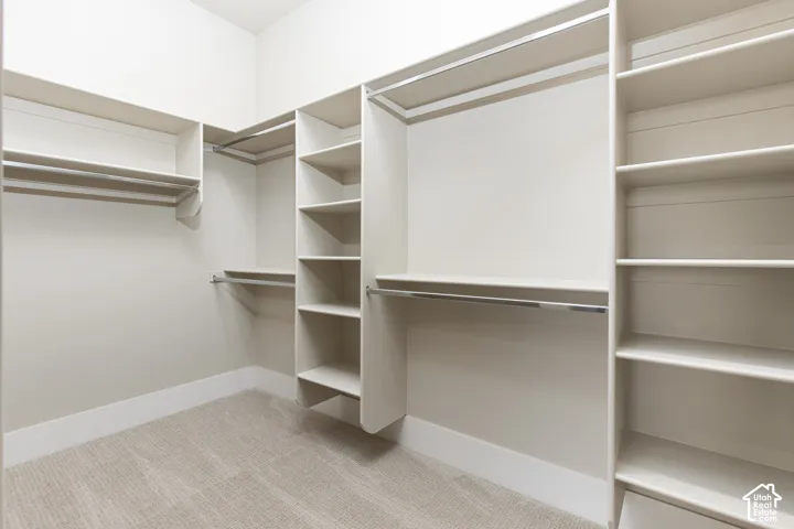 Walk-in closet featuring built-in shelving, multiple hanging rods, and neutral-toned carpeting