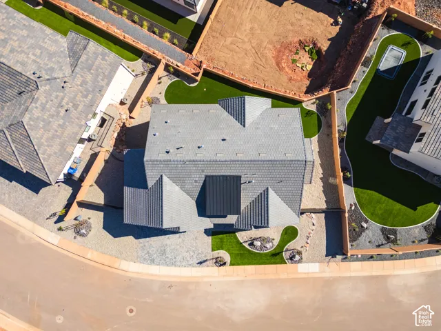 Pitched rooflines with varied textures, artificial turf landscaping, and paved pathways around the perimeter