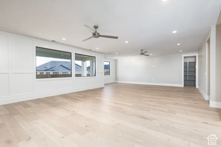 Expansive room featuring light wood-finish flooring, recessed lighting, and multiple ceiling fans