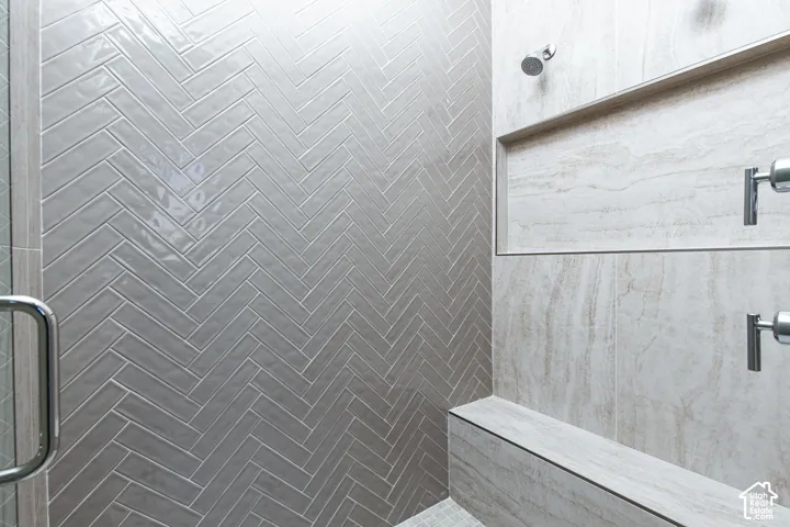 Herringbone tile shower wall, built-in shower bench, tiled shower niche, and polished chrome fixtures