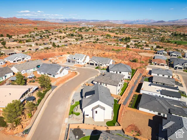 Curved residential street with a desert landscape backdrop, featuring multiple single-story and multi-story homes