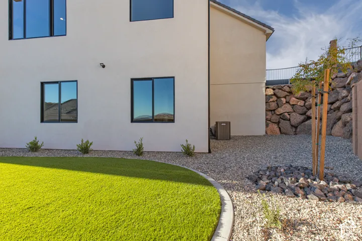Synthetic turf lawn with a curved concrete border, stone landscaping, and a natural stone retaining wall