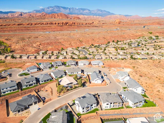 Residential community featuring paved roads, consistent roofing materials, and arid landscaping, set against a mountainous backdrop