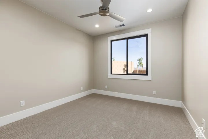 Bright secondary bedroom showcasing neutral wall finishes, recessed ceiling lighting, a ceiling fan, and a large picture window framing natural outdoor light