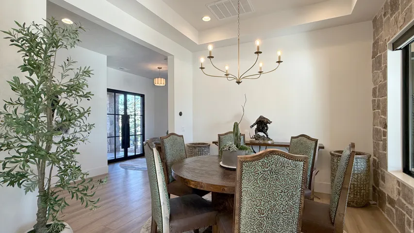 Tray ceiling with recessed lighting, chandelier, wood-finish flooring, accent stone wall, and a large window with a dark frame