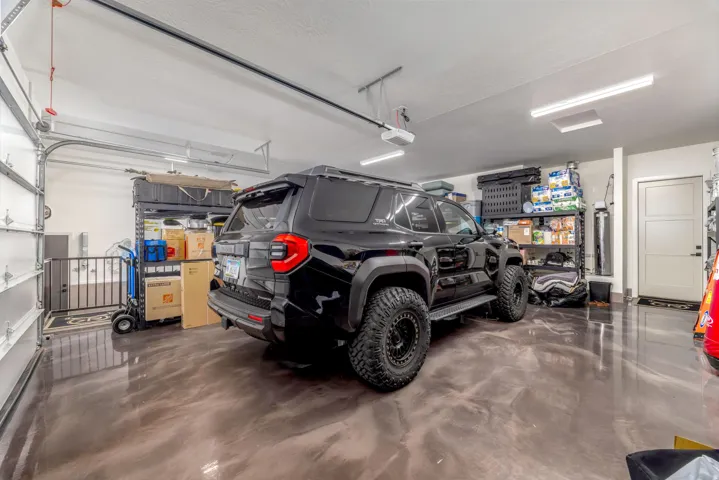 Finished garage with a metallic epoxy floor, overhead lighting, and an automatic garage door opener