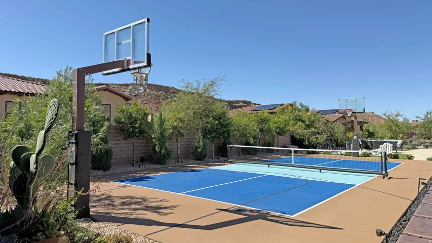 Multi-sport court featuring pickleball lines, basketball hoop, and a perimeter of desert landscaping