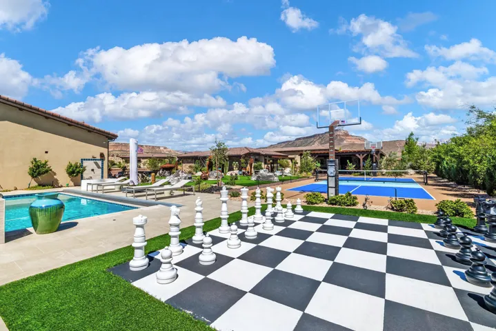 Outdoor living space featuring a swimming pool, a large-scale chess board, and a multi-sport court with a basketball hoop