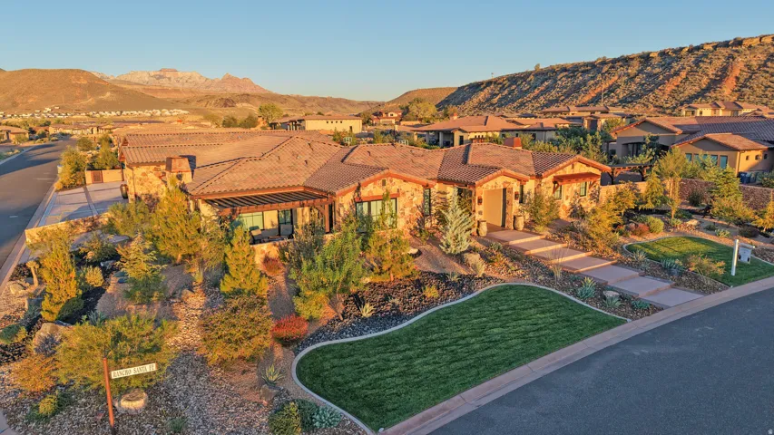 Stone exterior with a tile roof, complemented by a landscaped front yard with a manicured lawn and mature plantings