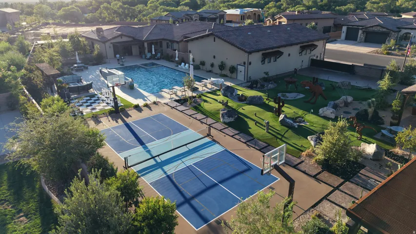 Expansive outdoor living area featuring a pool, a dedicated sport court, and a landscaped yard with artificial turf