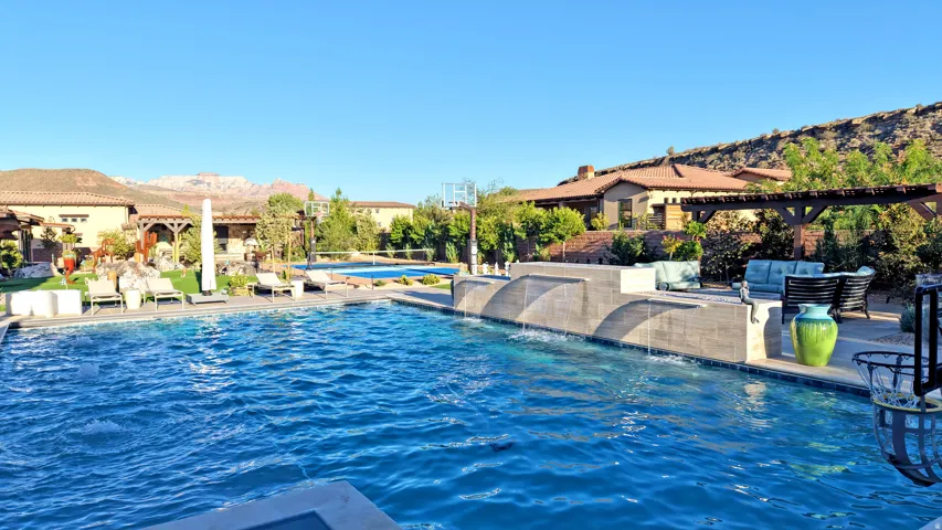 Expansive pool with integrated water features, a separate wading pool, and a stone-tiled spa