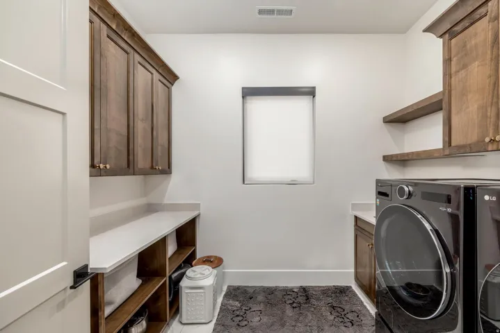 Wood-finish cabinetry, white countertops, built-in shelving, and a single window