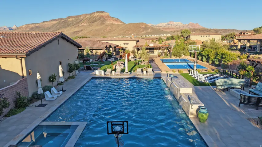 Expansive outdoor living area featuring a large swimming pool, integrated spa, and a dedicated sports court