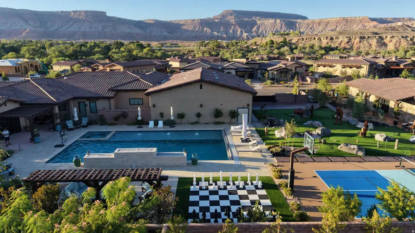 Expansive backyard featuring a large swimming pool, integrated spa, artificial turf lawn, a life-sized chess board, and a sports court
