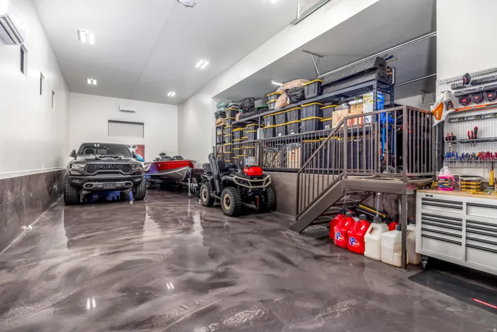 Spacious garage featuring a durable epoxy floor, integrated storage shelving, a built-in workbench, and multiple lighting fixtures