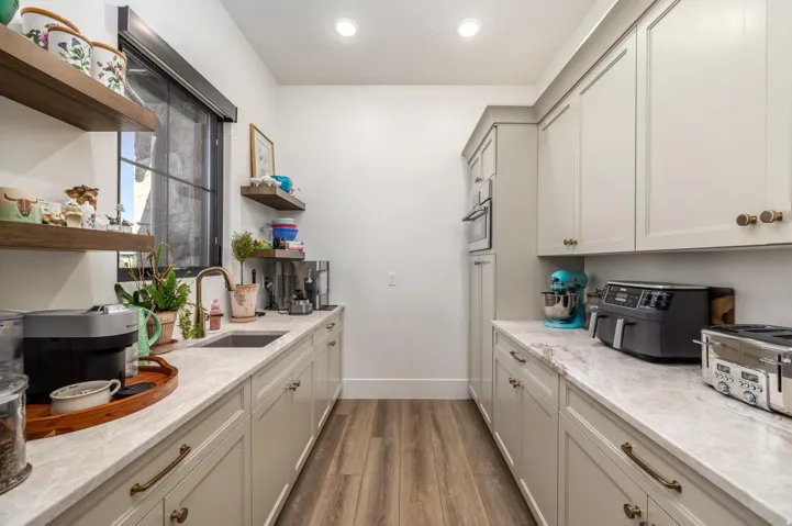 Butler's pantry featuring light-toned cabinetry, light-toned countertops, wood-finish flooring, and open wood shelving
