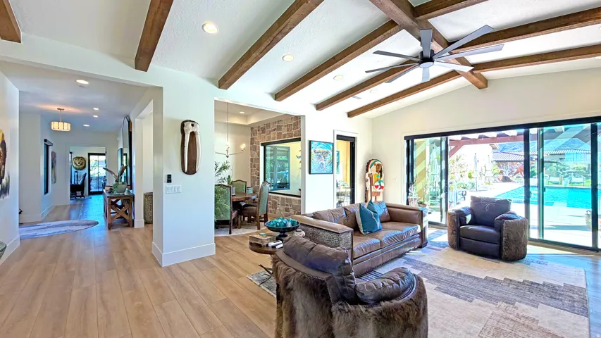 Vaulted ceilings with exposed wood beams, wood-finish flooring, recessed lighting, and a modern ceiling fan