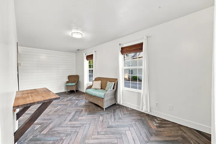 Herringbone wood-finish flooring, white shiplap accent wall, flush mount ceiling light, and built-in folding table