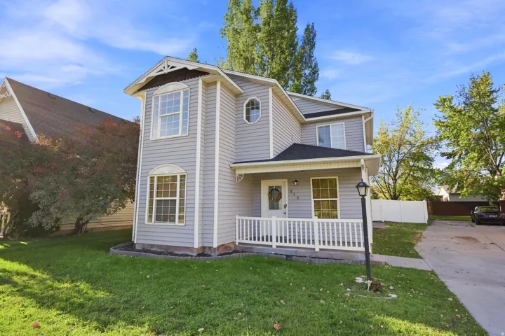 Two-story residence featuring light gray siding, a covered porch with white railing, and a black asphalt shingle roof