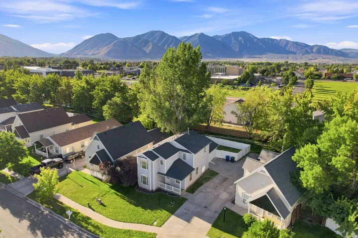Mountain backdrop, mature trees, expansive green spaces, residential setting, paved driveways