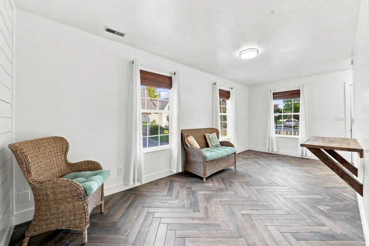 Herringbone wood-finish flooring, white walls, multiple windows with blinds, a flush mount ceiling light, and a built-in wood shelf