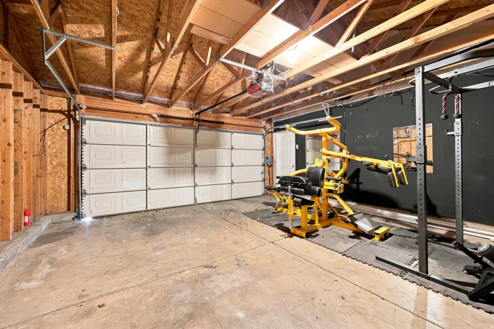 Attached garage with exposed wood beam ceiling, concrete flooring, and an overhead garage door