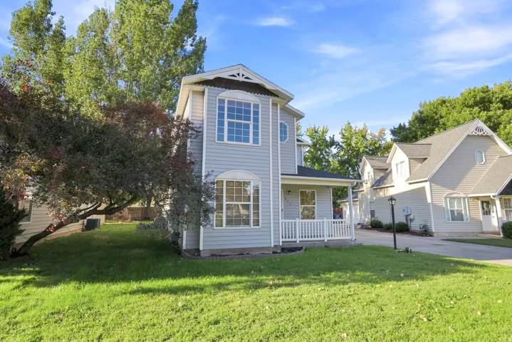 Two-story residence featuring light blue siding, multiple bay windows, and a covered front porch with white railings