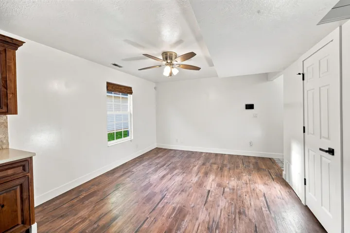 Wood-finish flooring, recessed ceiling detail, and a ceiling fan with integrated lighting
