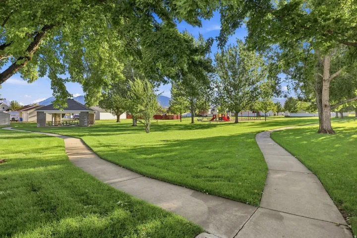 Expansive green space featuring mature trees and paved walking paths