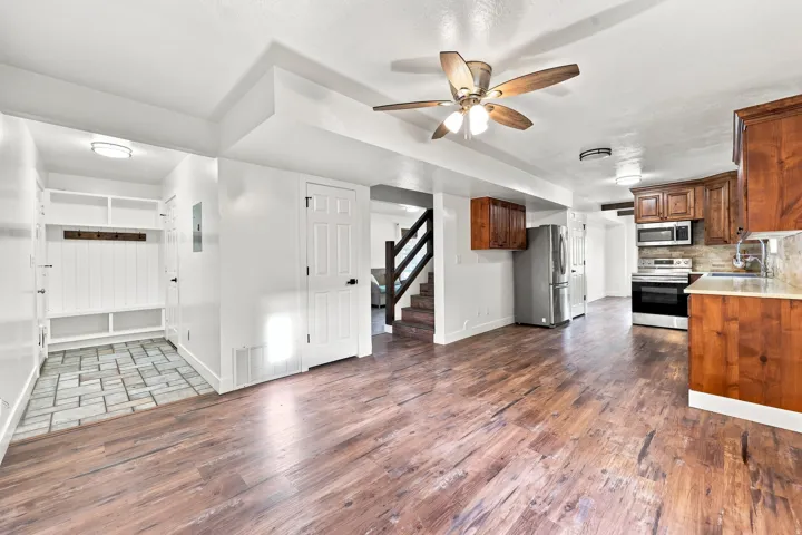 Wood-finish flooring throughout, kitchen with wood cabinetry and stainless steel appliances, built-in mudroom storage, and ceiling fan
