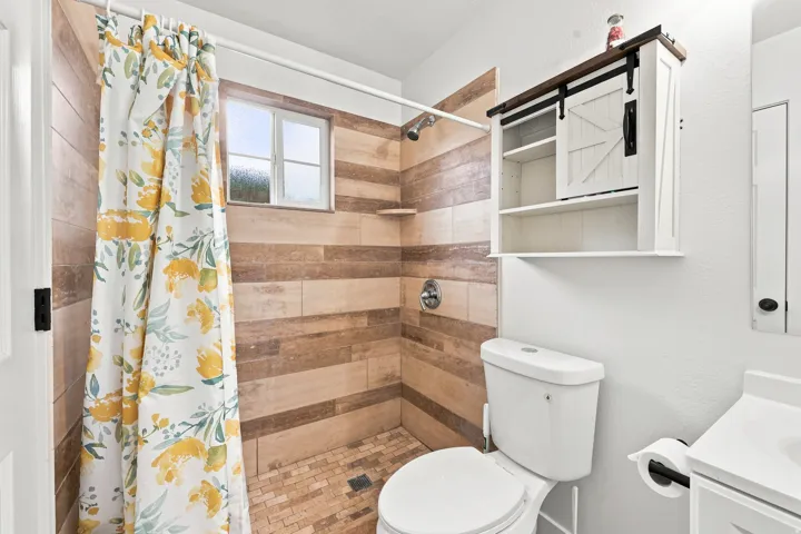 White toilet with a wall-mounted barn door style cabinet