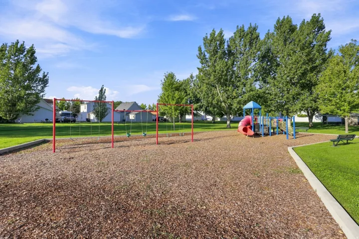 Outdoor recreation area with a playground structure, swings, and natural ground cover