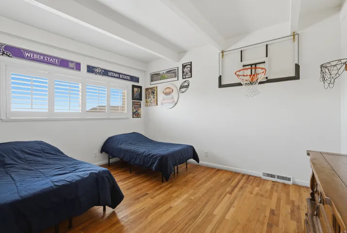 Bedroom #2.  Wood-finish flooring, white walls, and a window with white plantation shutters