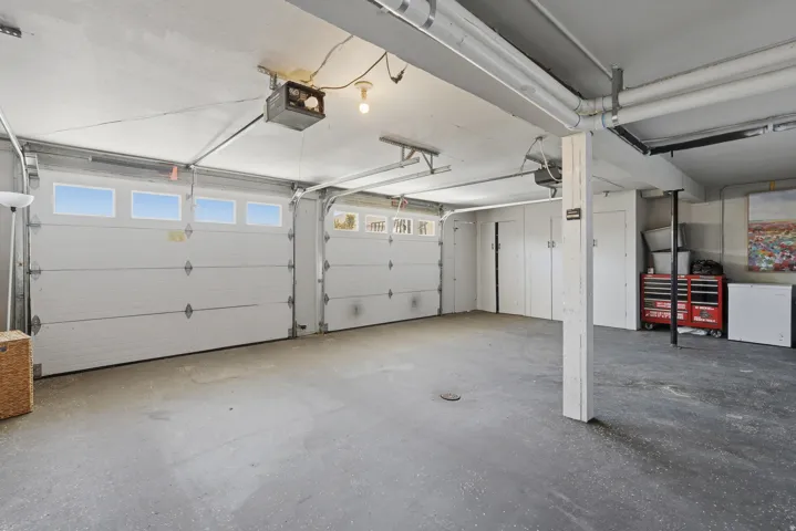 Spacious garage featuring two overhead doors with window panels, concrete flooring, and built-in storage closets
