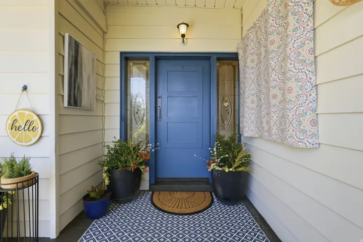 Entryway featuring a blue paneled door with glass sidelights and transom, exterior wall lighting, and horizontal siding