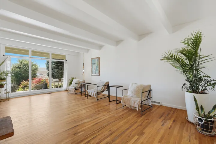 Vaulted ceiling with exposed beams, wood-finish flooring, and expansive windows